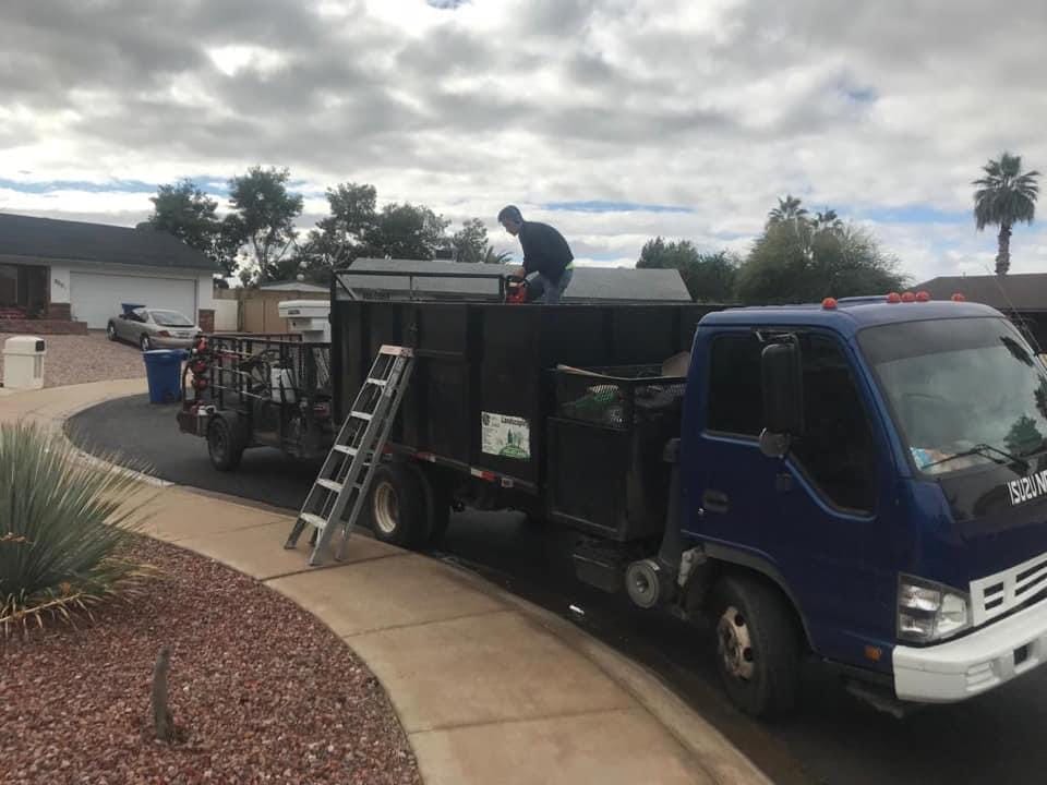 A man loading a garbage truck in front of a house.